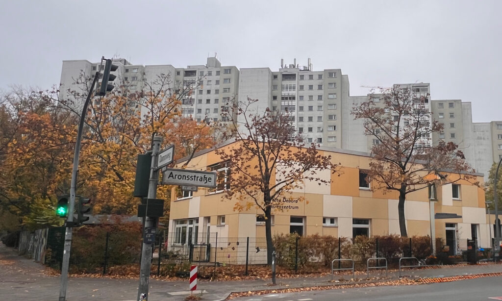Blick auf die Weiße Siedlung am Dammweg in Berlin-Neukölln. Davor steht ein flaches Gebäude mit einem Anstrich in Orange.